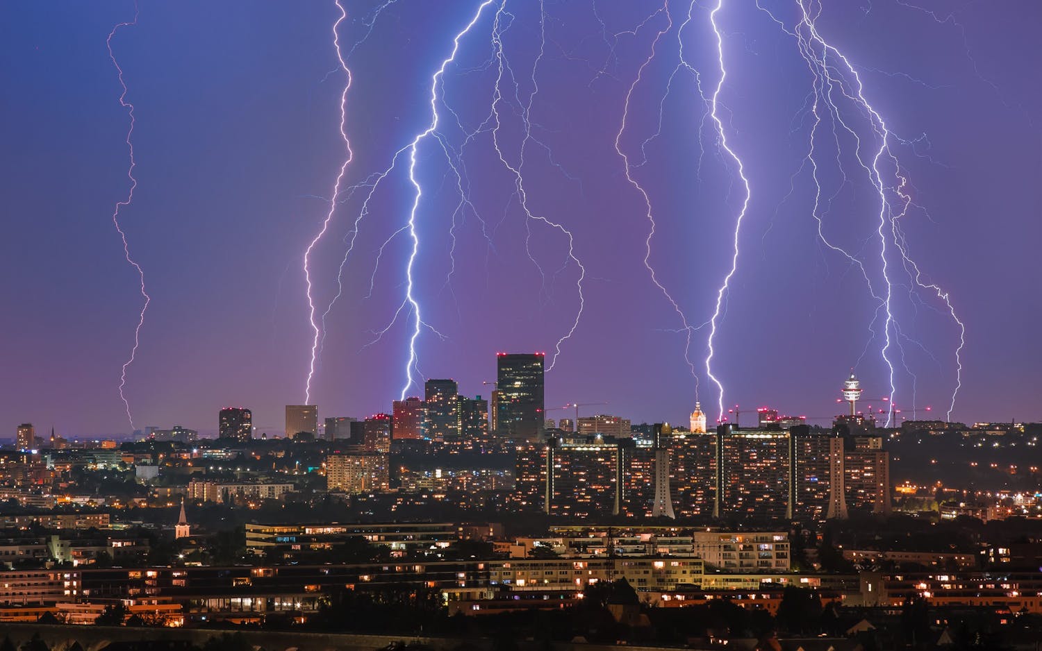 Runsaasti salamoita valaistun suurkaupungin yllä.